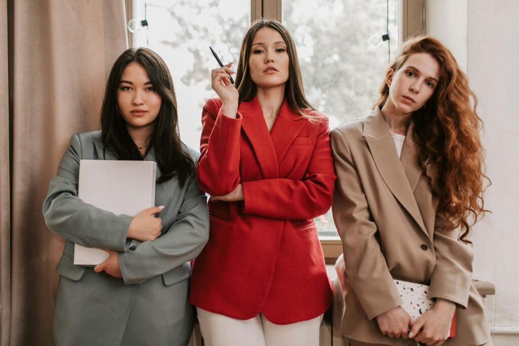 Three businesswomen in stylish blazers exuding confidence indoors.